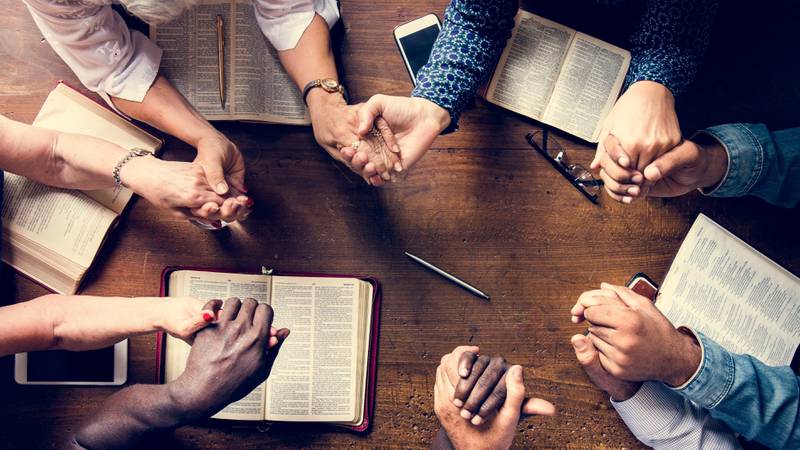 a group of people holding hands praying